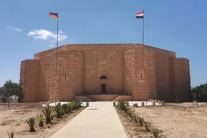 El Alamein WWII memorial building with Egyptian and German flags on private tour from Alexandria