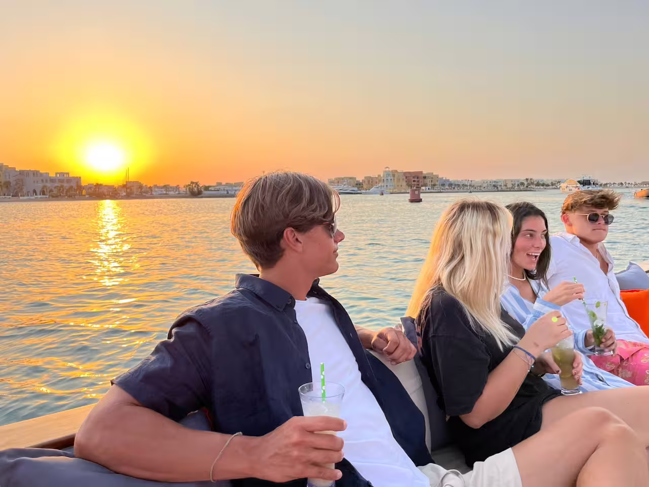 Friends relax with drinks on a sunset boat cruise in El Gouna lagoon, Red Sea city tour experience