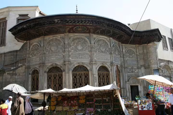 Ornate historic Cairo facade on El-Moez Street with market stalls near Khan El Khalili bazaar