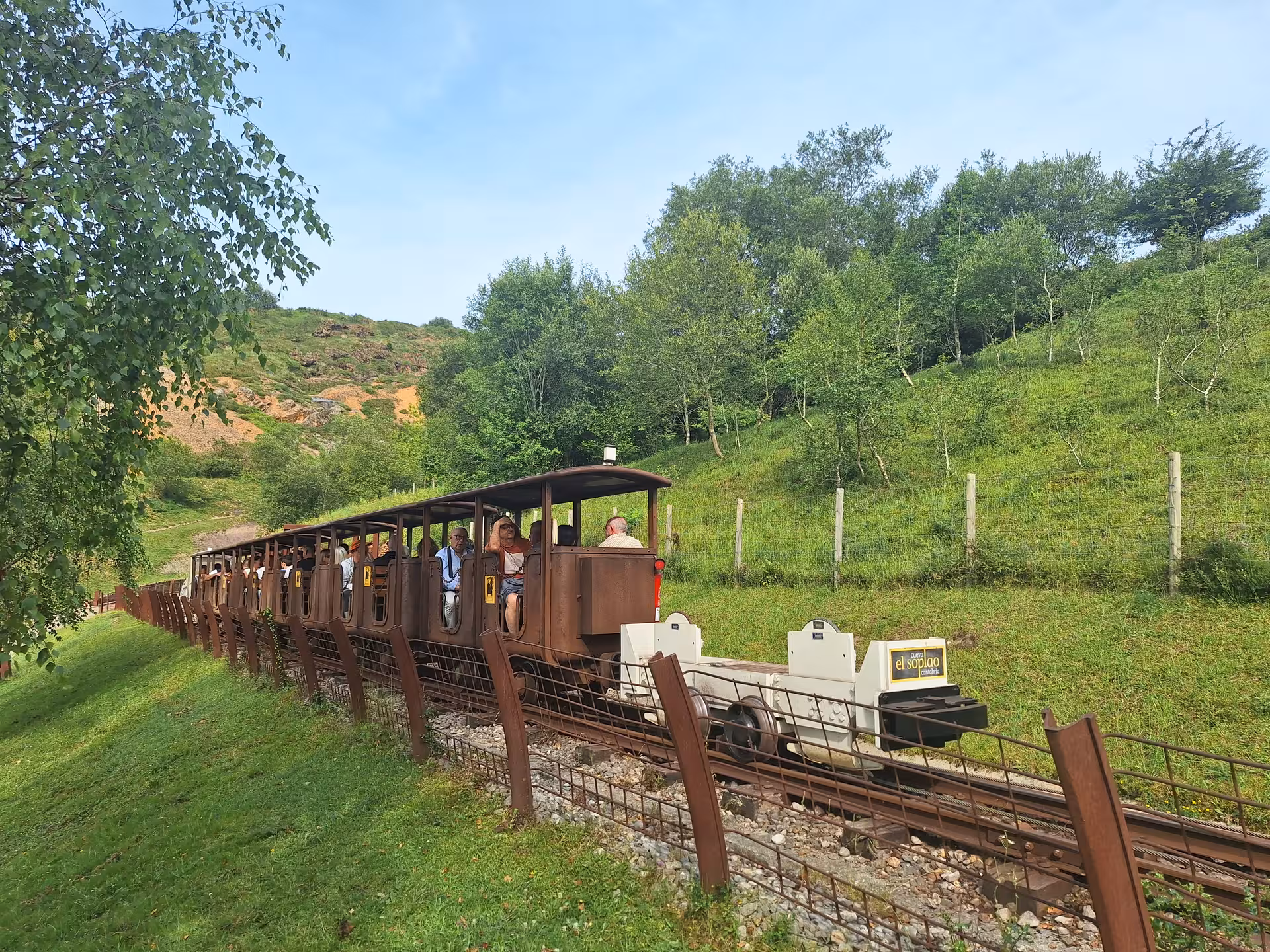Open-air train carrying visitors through lush landscapes on El Soplao Cave tour from Santander and Torrelavega.