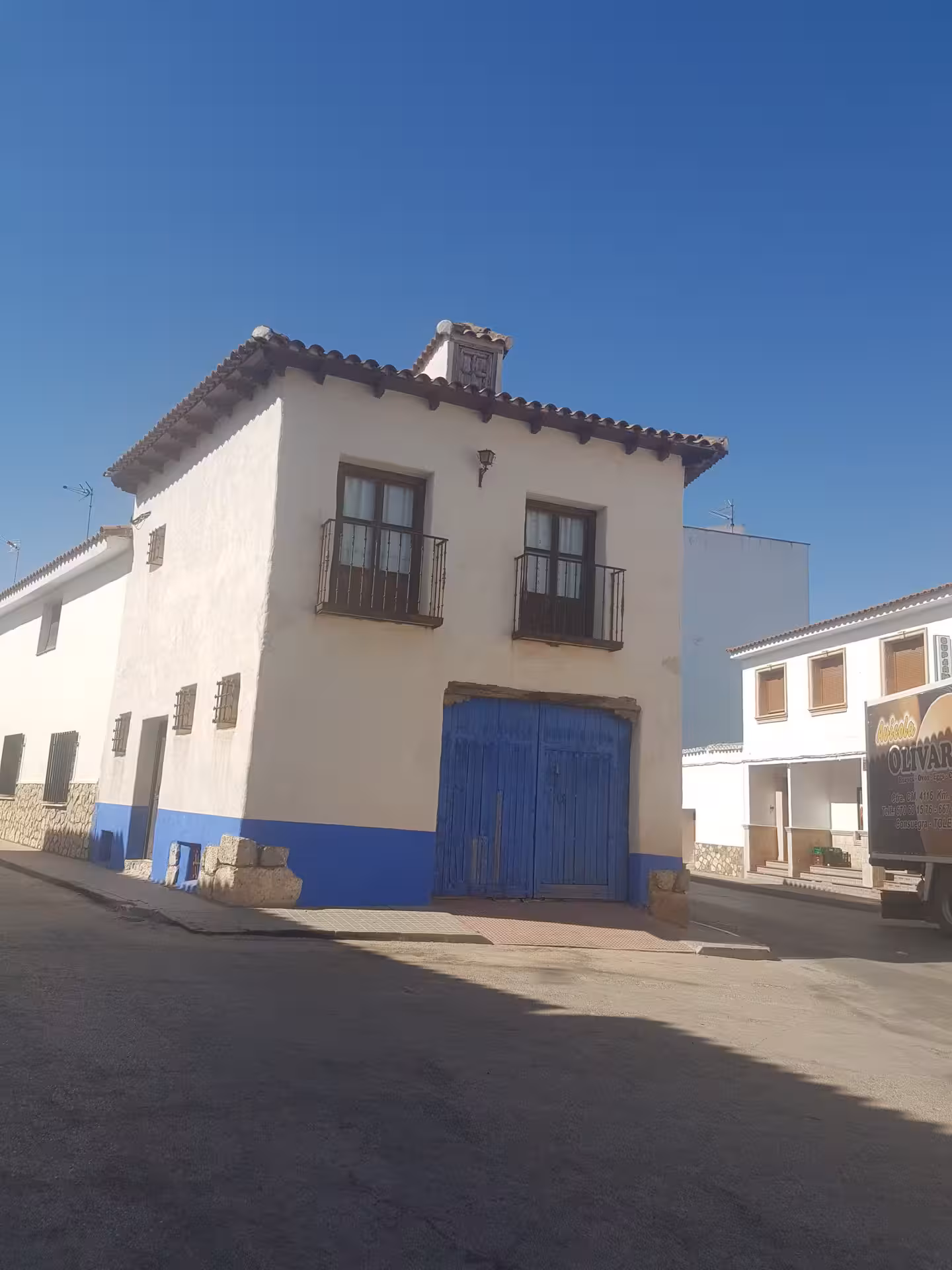 Whitewashed El Toboso street with blue door, scenic village stop on Don Quixote Tour through La Mancha, Spain