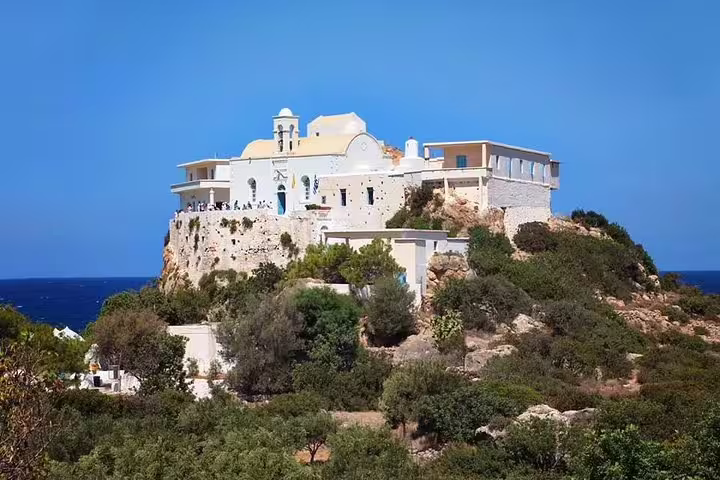 Historic seaside monastery on a rocky hill surrounded by lush greenery, part of the Elafonisi Beach private tour from Chania.