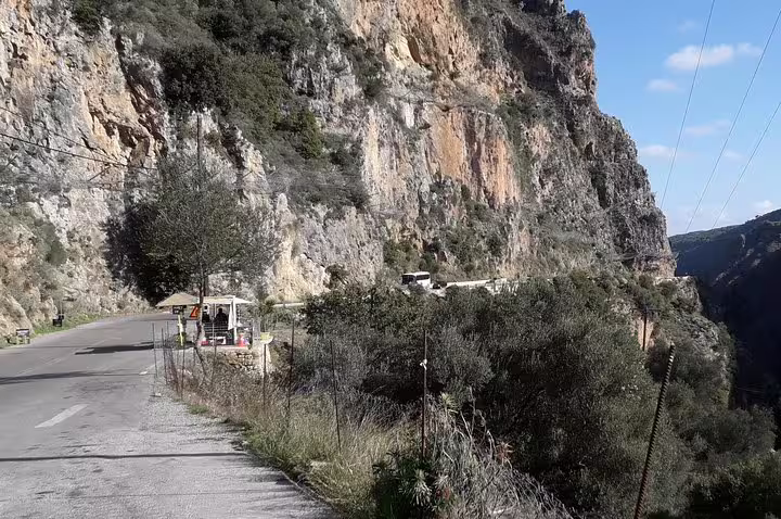 Scenic mountain road en route to Elafonisi Beach from Chania, showcasing rugged cliffs and lush greenery under a clear blue sky.