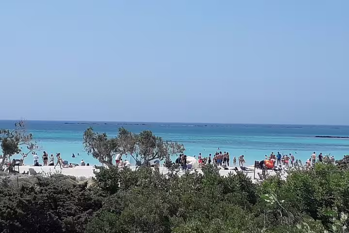 Tourists enjoy the stunning turquoise waters and unique pink sand of Elafonisi Beach on a private tour from Chania.