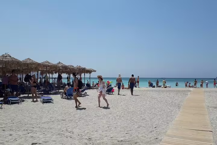 Tourists enjoy the sun on the sandy shores of Elafonisi Beach during a private tour from Chania, highlighting the famous pink sands.