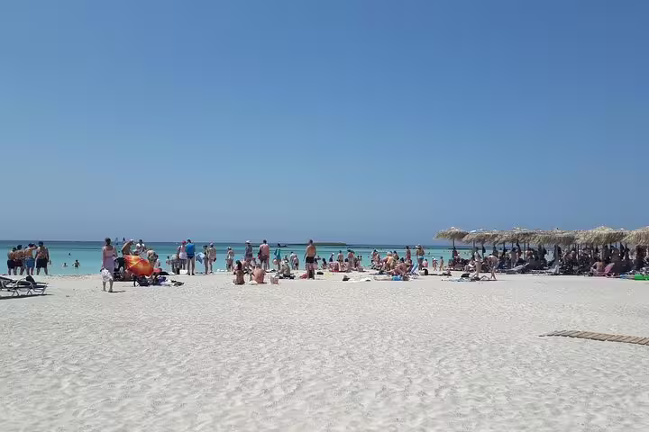 Tourists enjoy the sun and turquoise waters on the pink sands of Elafonisi Beach during a private tour from Chania.
