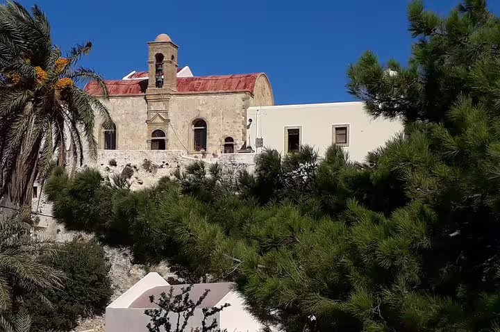 Historic stone church surrounded by lush greenery under a clear blue sky, seen on a private tour to Elafonisi Beach from Chania.