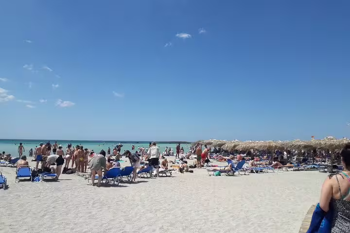 Visitors enjoy the white sands and clear waters of Elafonissi Beach under a bright blue sky, ideal for a private tour.