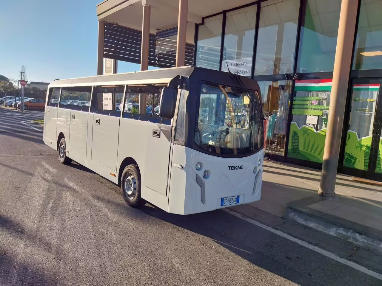 Electric minibus parked outside a modern building in Pisa, ideal for eco-friendly city tours and sustainable travel.