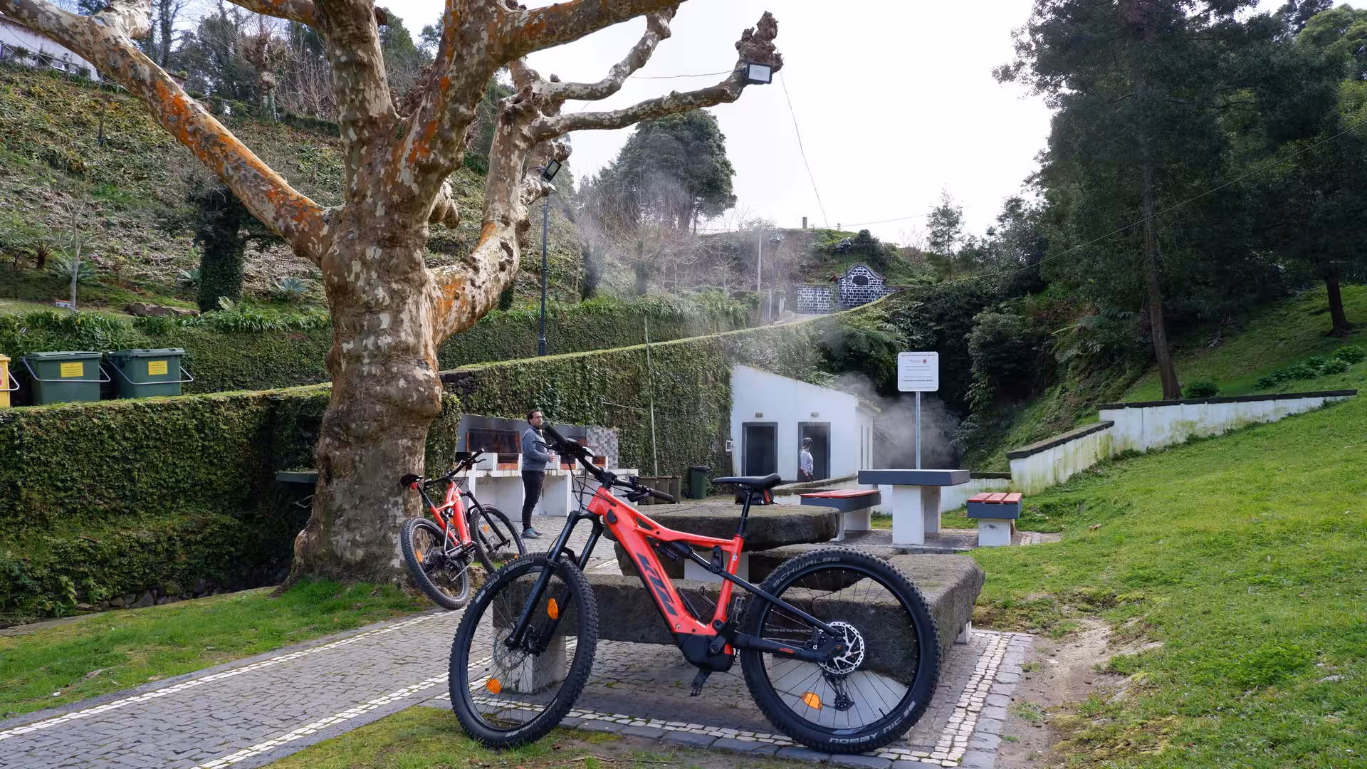 Electric mountain bikes parked by hot springs and picnic area on a green hillside in Ribeira Grande, São Miguel, Azores