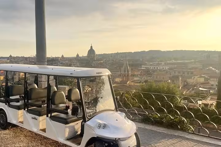 Electric tour vehicle overlooking Rome's skyline at sunset, showcasing iconic landmarks for The Great Beauty tour.