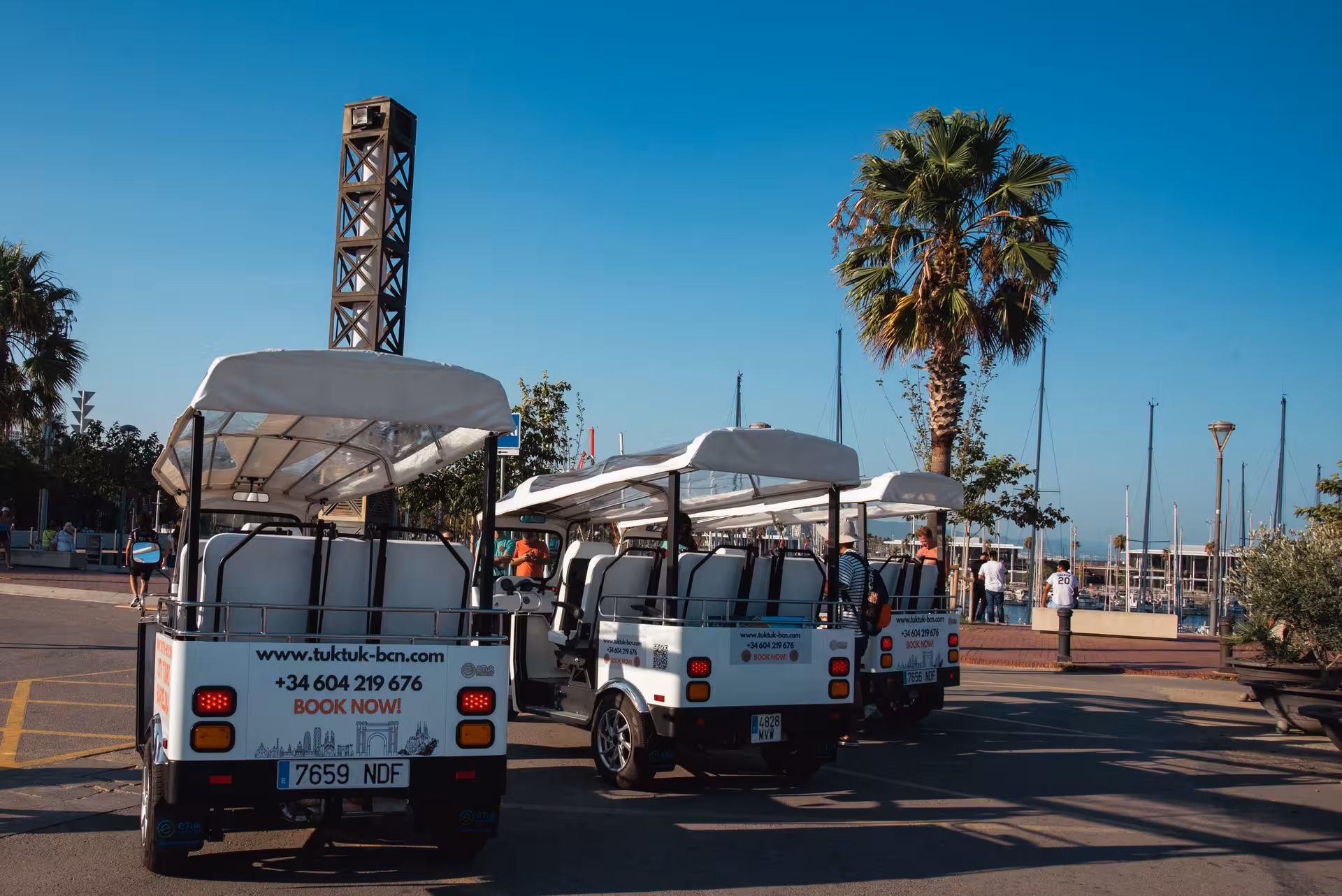 Electric tuk tuks lined up at Port Vell marina, a scenic start point for the Welcome Tour Barcelona sightseeing ride