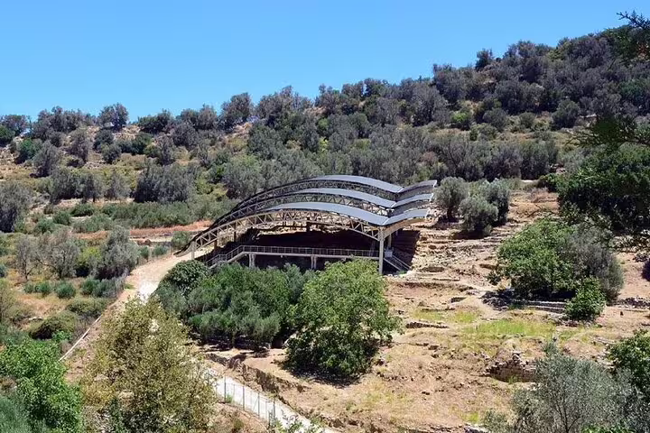 Archaeological site of Eleftherna with modern protective structure amidst lush greenery.