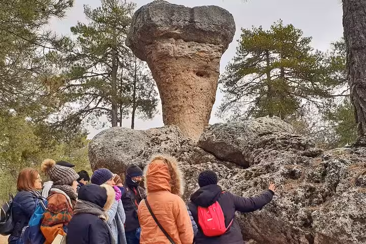 Travelers admiring mushroom-shaped rock in the Enchanted City from Cuenca excursion to Ventano del Diablo