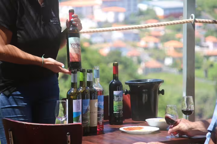 Wine tasting setup at Enchanted Vineyards with various bottles, glasses, and a scenic backdrop on the Wine 4x4 Tour in Cabo Girão.