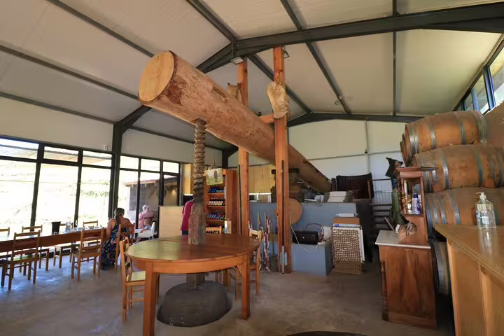 Rustic winery interior with large wooden beams, wine barrels, and seating, part of Enchanted Vineyards 4x4 Sea Cliff Tour.