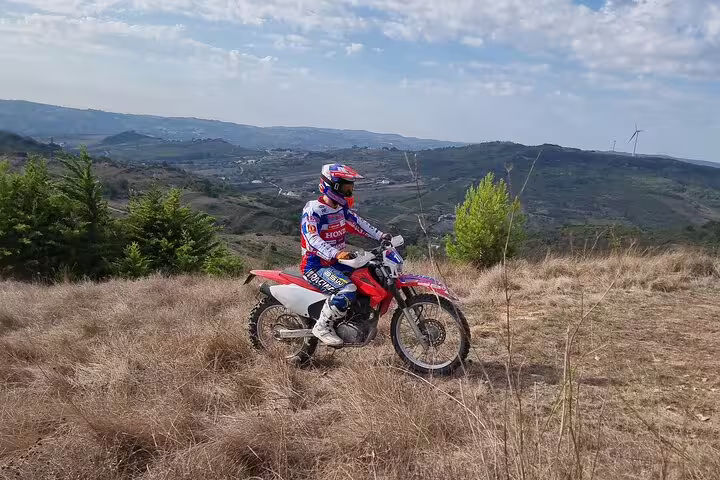 Enduro rider pauses to enjoy panoramic views of Lisbon's landscapes on a guided tour.