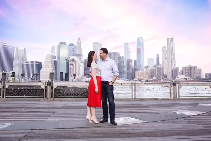 Engaged couple posing on Brooklyn Bridge Park pier with NYC skyline, New York proposal photographer shoot