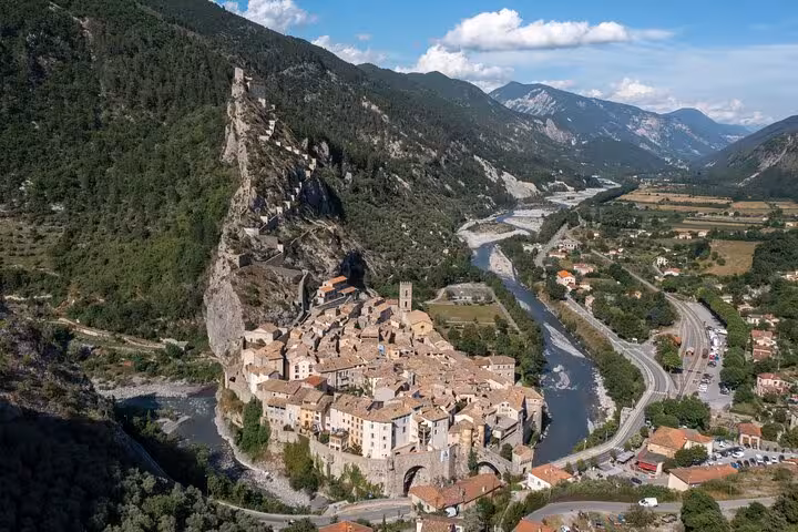 Aerial view of the medieval village of Entrevaux nestled in a lush valley, showcasing its historic architecture and river.