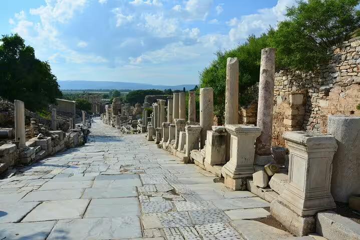 Scenic marble-paved Curetes Street lined with ancient columns in Ephesus under a bright blue sky.
