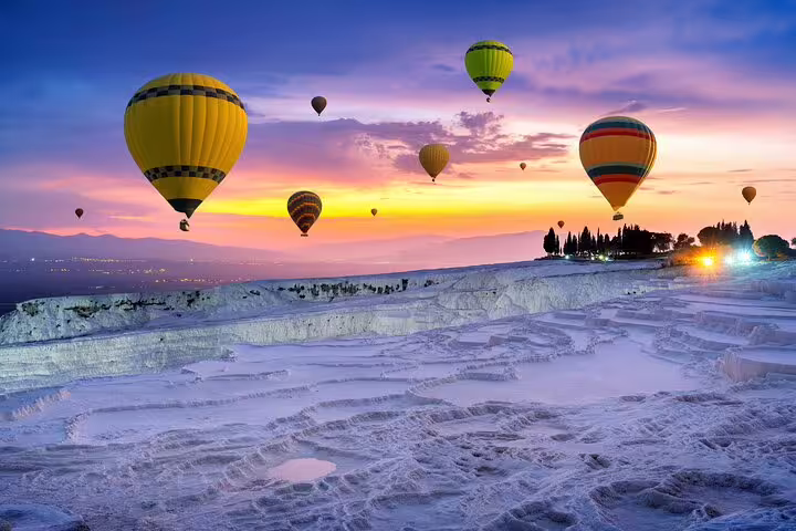 Experience stunning hot air balloons over Pamukkale's travertine terraces at sunrise on a tour from Kusadasi and Selcuk.