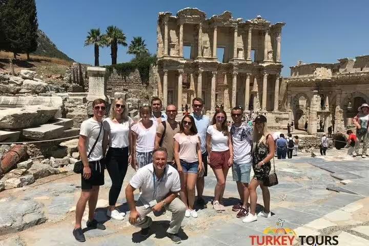 Large tour group gathered in front of the iconic Library of Celsus in Ephesus, enjoying a sunny day.