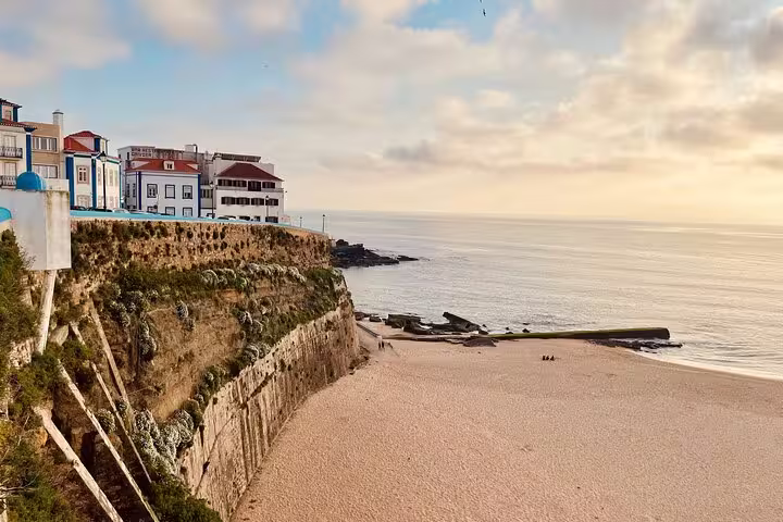 Scenic view of Ericeira's stunning cliffside beach at sunset, showcasing coastal beauty on the Mafra, Ericeira & Queluz tour.