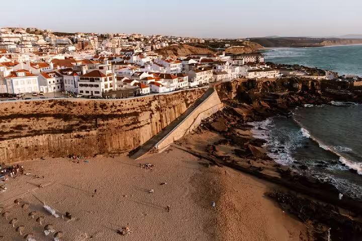Aerial view of Ericeira's stunning coastline with charming whitewashed houses on cliffs, perfect for the Mafra, Ericeira & Queluz tour.