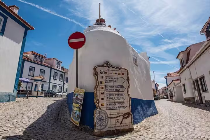 Charming cobblestone street in Ericeira with traditional white and blue buildings, perfect for a Mafra and Queluz day tour.