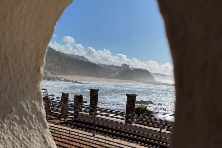 Scenic view of Ericeira's coastline framed by rocky cliffs and a sunny beach, ideal for a private tour from Sintra.