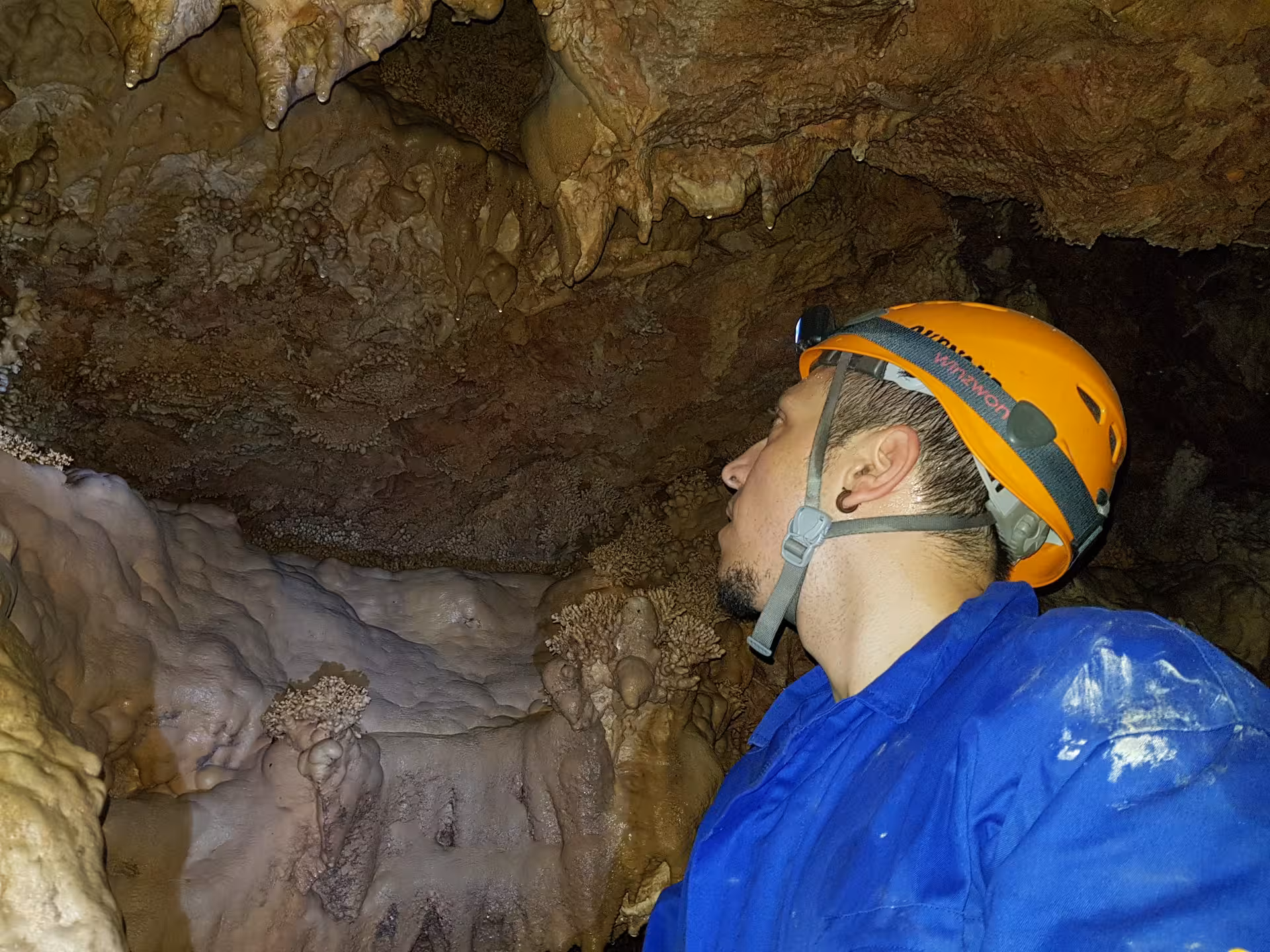 Espeleólogo con casco y frontal observando estalactitas en cueva de Ejulve, Teruel, iniciación