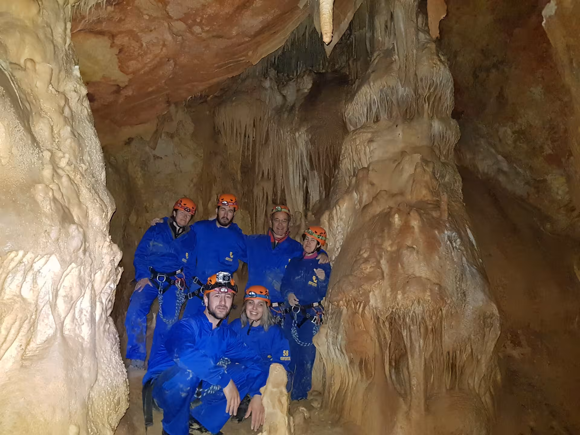Grupo de espeleología en Ejulve, Teruel, iniciación en cueva con cascos y monos junto a estalactitas