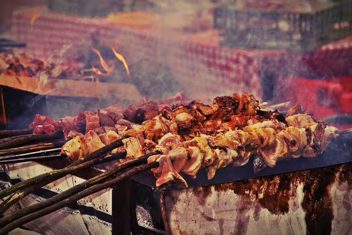 Traditional espetada skewers grilling over open fire at a vibrant Madeira night market, showcasing local cuisine.