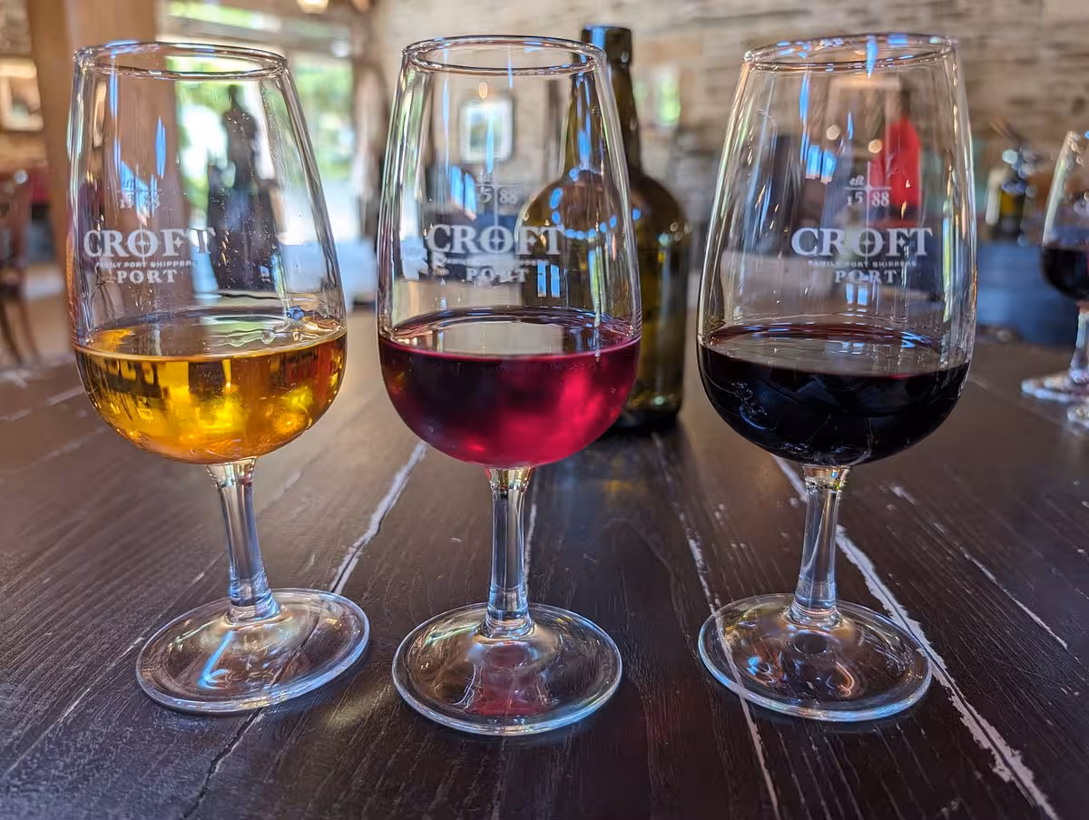 Essence Tour wine tasting with three Croft Port glasses on rustic table, Douro Valley winery experience