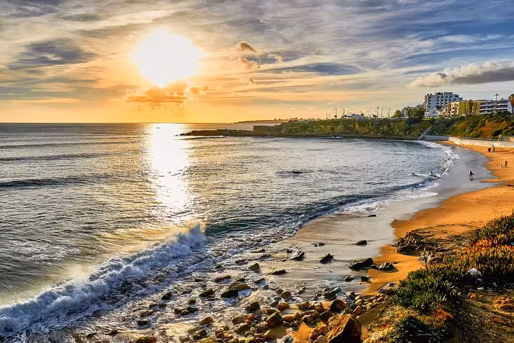 Sunset view over Estoril Beach with golden sands and gentle waves, perfect for a relaxing getaway from Lisbon.