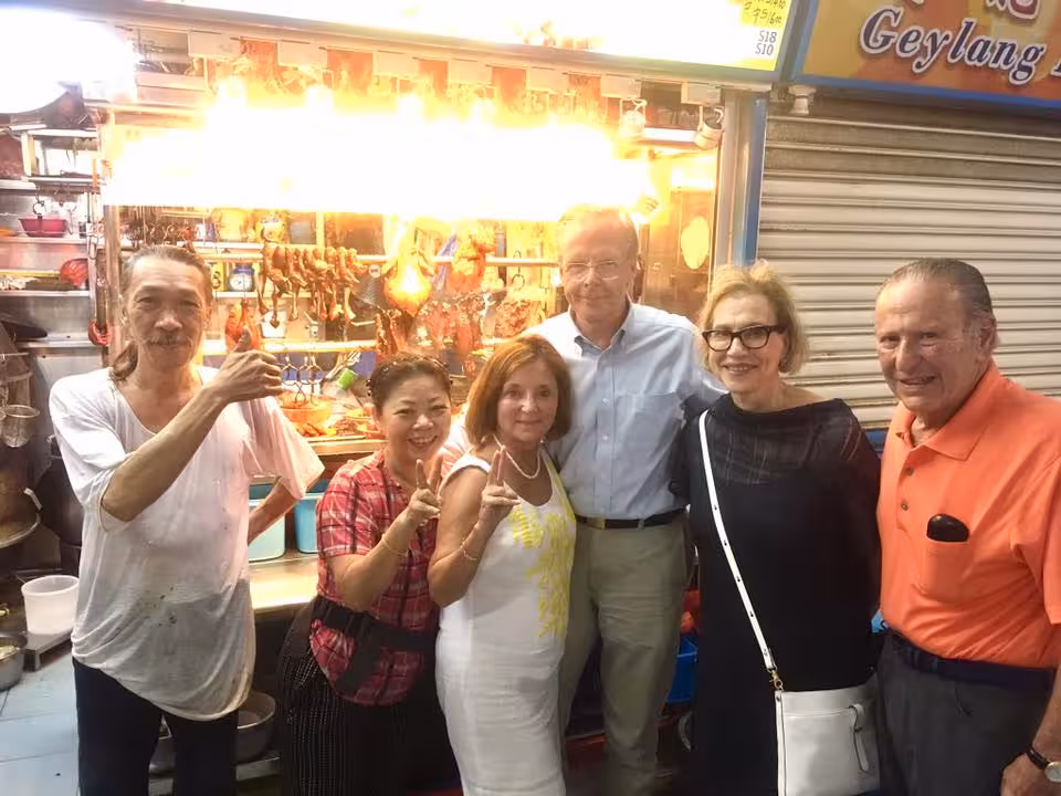 Visitors pose with locals at a vibrant street food stall in an ethnic neighborhood.