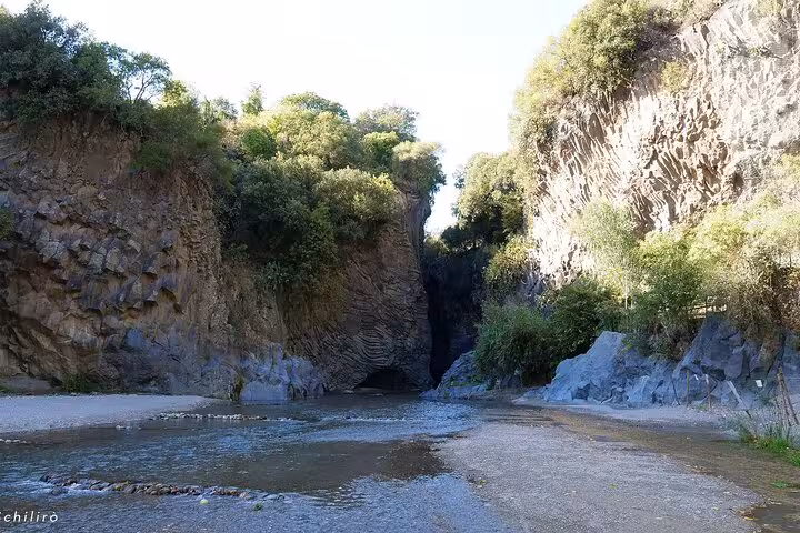 Scenic view of the Alcantara Gorge with towering cliffs and lush greenery on the Etna and Alcantara River tour.
