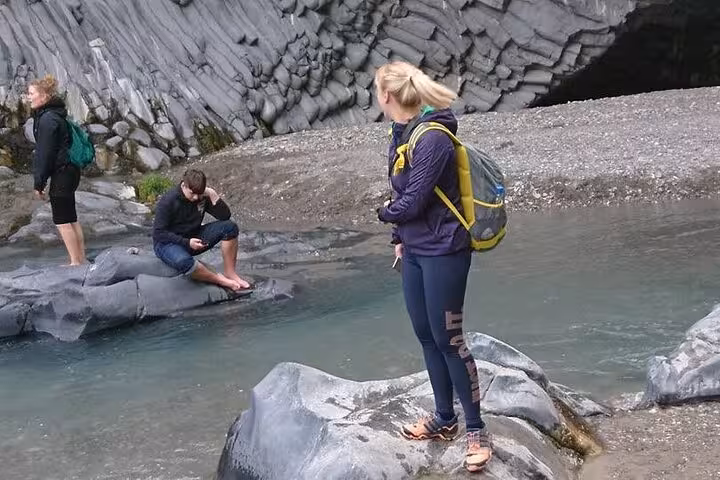 Tourists exploring the unique basalt formations along the Alcantara River, a highlight of the Etna and Alcantara tour.