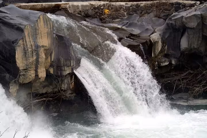 Witness the majestic waterfall cascading over volcanic rocks at Alcantara Gorge on the Etna and Alcantara River Tour.