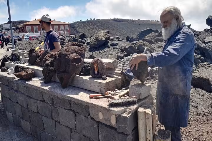 Craftsmen showcasing volcanic stone sculptures near the summit of Mount Etna, capturing local artistic traditions.