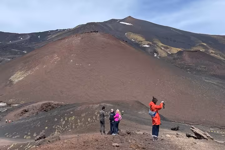 Visitors explore the rugged terrain of Mount Etna under a clear sky on the Etna Sunset Tour.