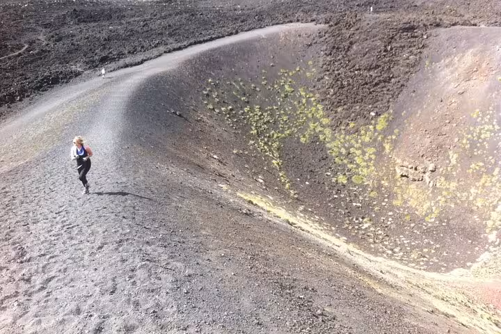 Hiker exploring rugged volcanic terrain on Mount Etna's crater, showcasing adventure and natural beauty.