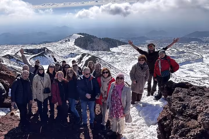 Tour group enjoying snowy views on Etna Sunset Tour with scenic volcanic landscape and clouds.