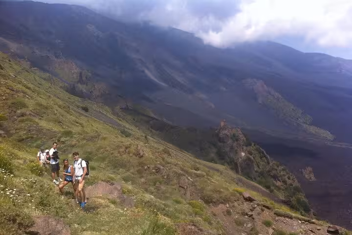 Group of hikers exploring lush slopes of Mount Etna on a sunny day during a trekking adventure tour.