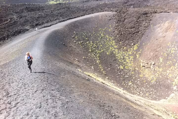 Hiker ascending the rugged terrain of a volcanic crater on Mount Etna, showcasing natural landscape.