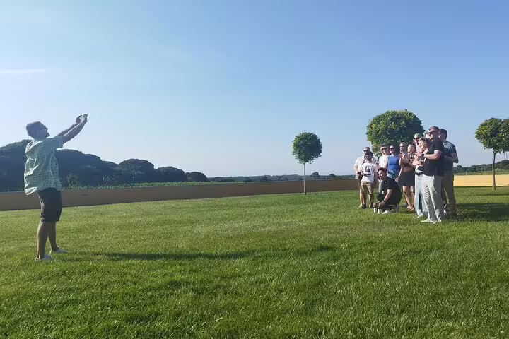 Tour group poses for a photo in a lush vineyard during the Private Full Day Évora & Alentejo Wine Tour from Lisbon.