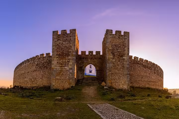 Experience the enchanting sunset view of a fortified castle in Évora, showcasing its majestic stone architecture.