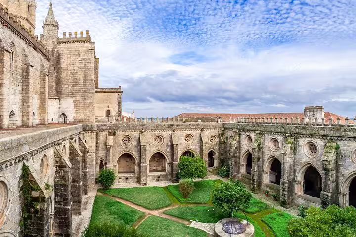 Historic courtyard of Évora Cathedral with intricate arches and lush greenery, featured in the Évora & Monsaraz full-day tour.