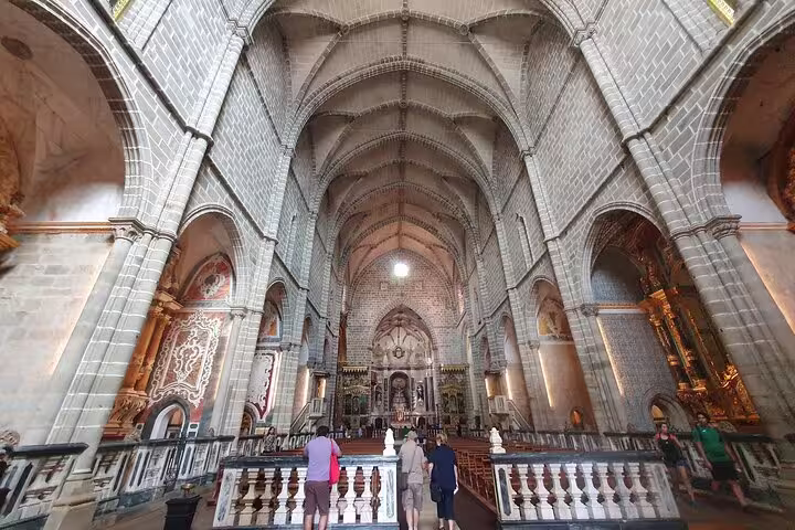 Interior view of Évora Cathedral with tourists exploring the stunning Gothic architecture on a guided tour from Lisbon.