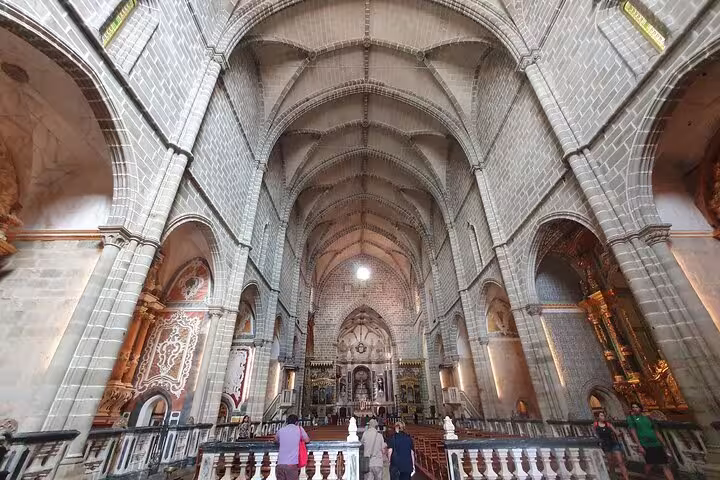 Visitors explore the stunning architecture of a historic cathedral interior in Évora during a private full-day tour from Lisbon.